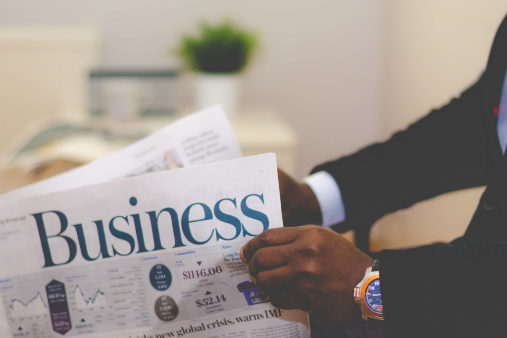 Man holding newspaper with the word business on it